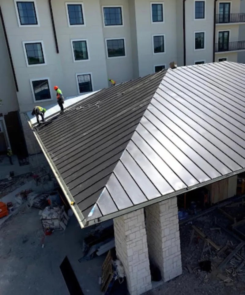 Crew installing standing seam metal roof panels on a commercial project in Irondale